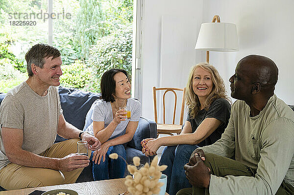 Portrait of two diverse couples chatting while having a drink indoors