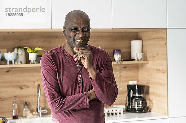Porträt eines afroamerikanischen Mannes mittleren Alters  der in der Küche in die Kamera lächelt