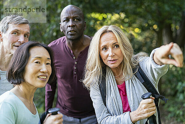 Senior woman giving directions to diverse group of people while pointing