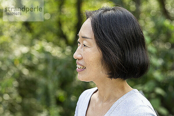 Side view shot of senior Asian-American woman standing outdoors