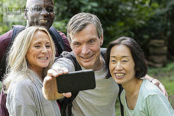 Lustige  vielfältige Gruppe von Freunden mittleren Alters  die im öffentlichen Park ein Selfie machen