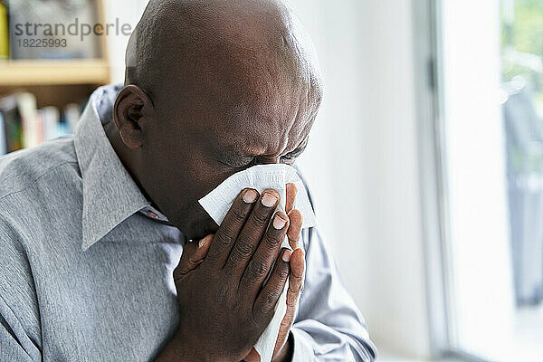 Nahaufnahme eines älteren afroamerikanischen Mannes  dem eine Erkältung die Nase putzt