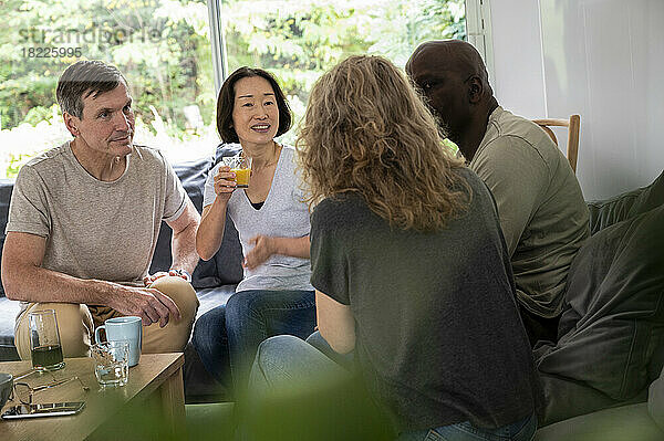 Group of diverse male and female friends sitting in living room enjoying their conversation