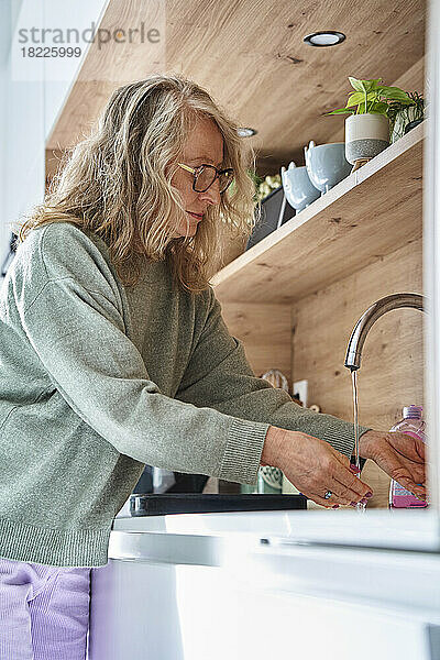 Ältere Frau wäscht in der Küche