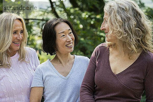Drei Frauen mittleren Alters unterhalten sich freundlich in ihrem Hinterhof