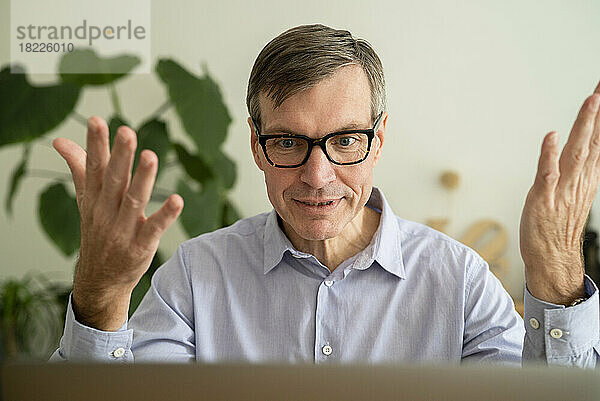 Älterer Mann bei einem Online-Meeting auf dem Laptop  während er zu Hause arbeitet