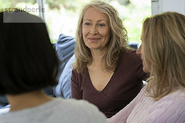 Portrait of senior woman chatting with her two friends at home
