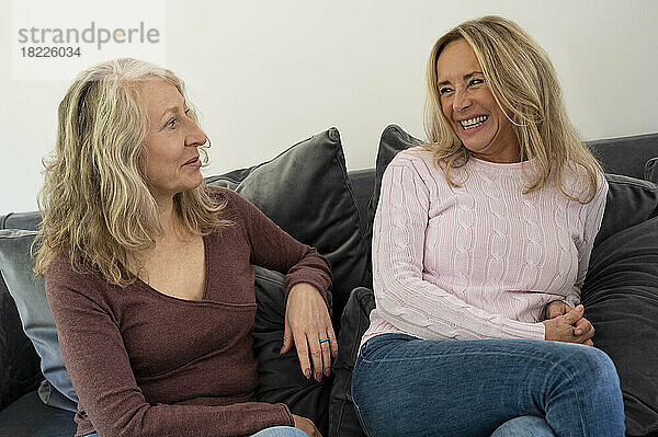 Porträt zweier älterer Freundinnen  die sich zu Hause auf der Couch vergnügen