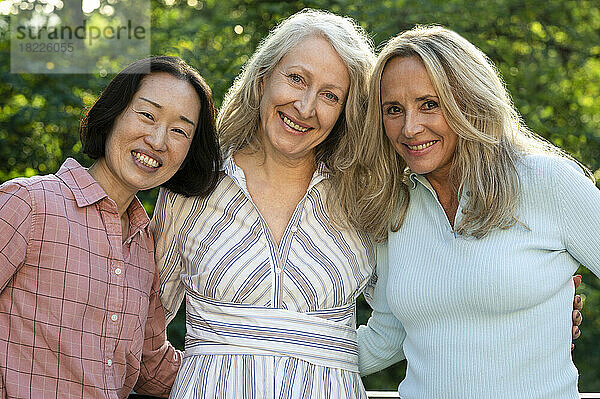 Drei ältere Frauen posieren gemeinsam für ein Gruppenfoto im Freien