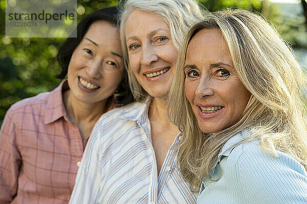 Drei ältere Frauen posieren gemeinsam für ein Gruppenfoto im Freien