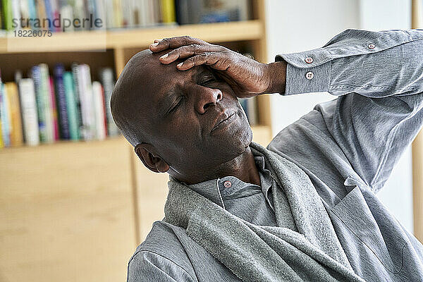 Afroamerikanischer Mann mittleren Alters hält sich vor Schmerzen den Kopf