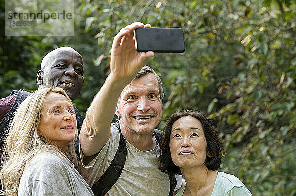Lustige  vielfältige Gruppe von Freunden mittleren Alters  die im öffentlichen Park ein Selfie machen
