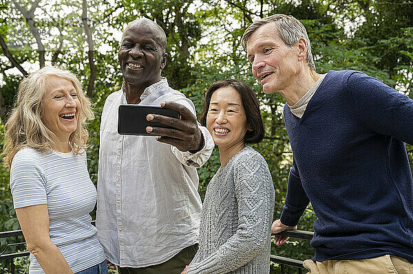 Portrait of diverse couples having fun while taking a selfie in public park
