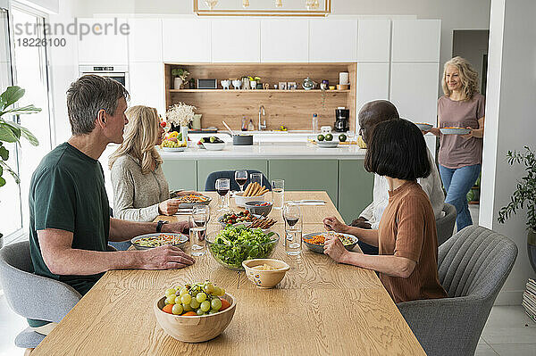Eine Gruppe verschiedener Freunde mittleren Alters versammelte sich zum Abendessen in der Küche