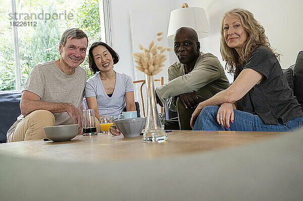 Porträt einer vielfältigen Gruppe älterer Freunde  die sich zu Hause amüsieren und in die Kamera schauen
