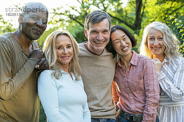 Fun diverse group of middle-aged friends hanging out in backyard at sunset