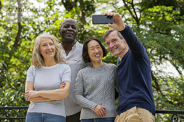 Portrait of diverse couples having fun while taking a selfie in public park