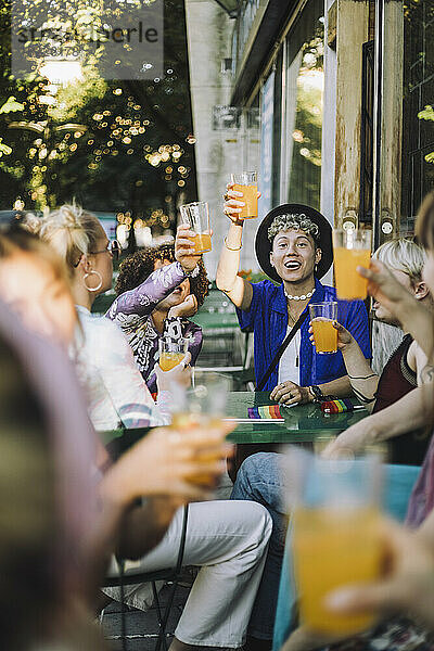 Glücklicher junger Mann genießt ein Getränk  während er mit Freunden zusammensitzt