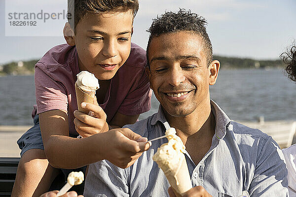 Glücklicher Vater teilt Eis mit seinem Sohn während des Sommerurlaubs