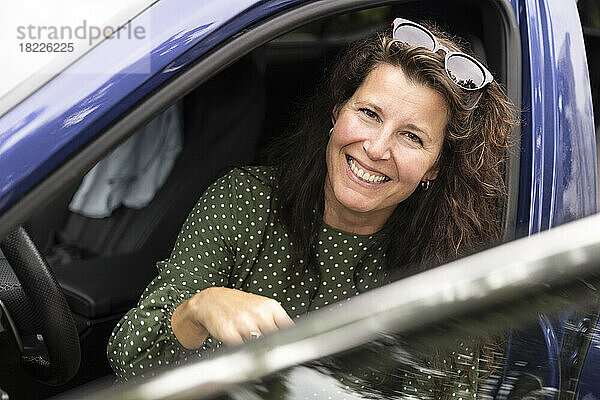 Porträt einer glücklichen Frau mit Sonnenbrille im Auto sitzend