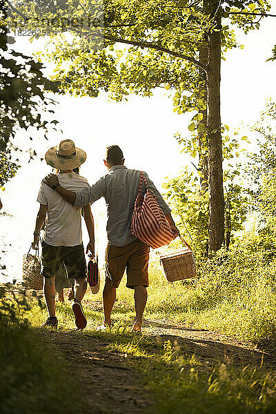 Rückansicht des Vaters mit Arm um den Sohn beim Spaziergang im Wald im Urlaub