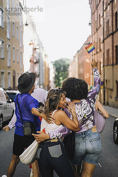 Glückliche junge Freunde gehen auf der Straße während der Gay Pride Parade