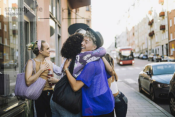 Glücklicher junger Mann mit geschlossenen Augen  der eine Freundin in der Stadt umarmt