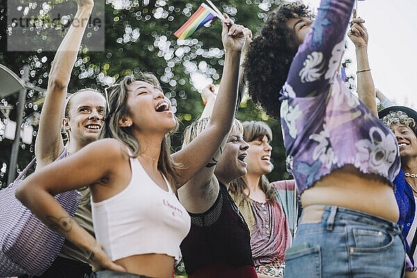 Fröhliche Freunde mit Regenbogenfahnen schreien bei der Parade für LGBTQIA-Rechte