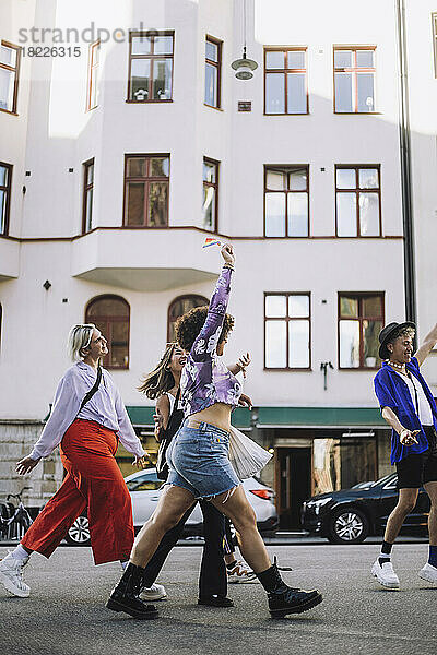 Junge LGBTQIA-Freunde auf dem Fußweg während der Gay Pride Parade