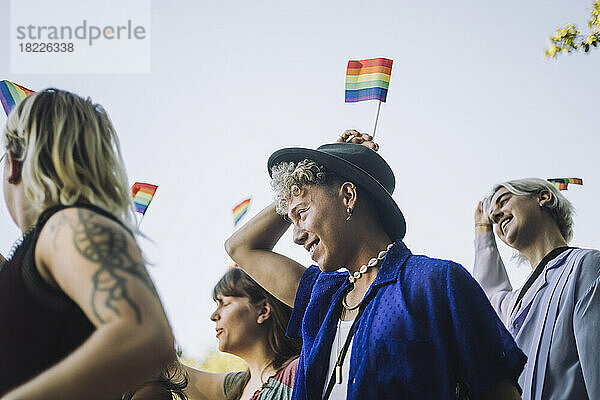 Ein lächelnder junger Mann genießt mit Freunden die LGBTQIA-Parade