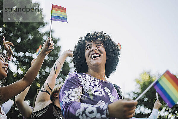 Glückliche Transgender-Frau mit Regenbogenfahne bei der Gay Pride Parade