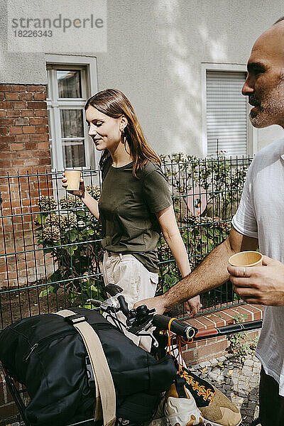 Junge Frau mit männlichem Freund  der mit dem Fahrrad fährt  während er Kaffee trinkt