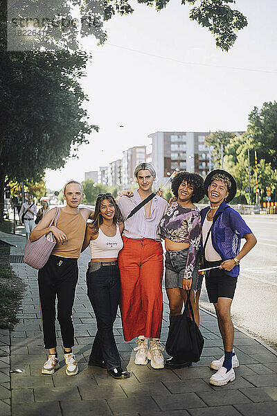 Porträt in voller Länge von lächelnden jungen LGBTQIA-Freunden  die auf einem Fußweg stehen