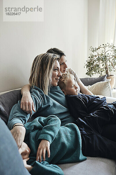 Lesbische Mütter sitzen mit ihren Söhnen zu Hause auf dem Sofa