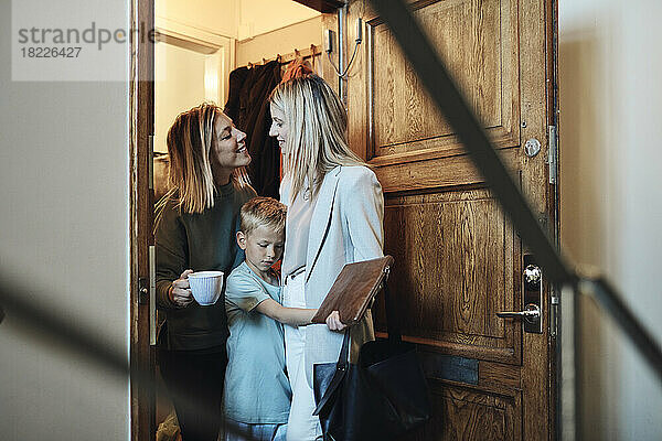 Lesbische Mütter schauen sich an  während sie mit ihrem Sohn vor der Tür stehen