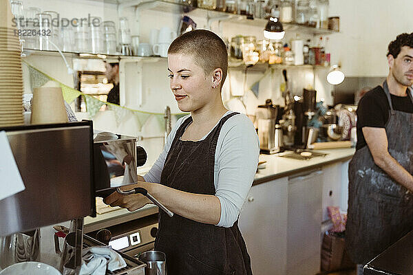 Junge Barista-Frau bereitet Kaffee in einem Café zu