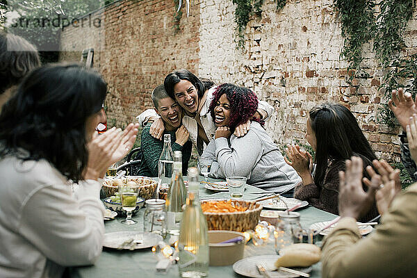 Multirassische Freundinnen  die während einer Dinnerparty im Hinterhof zusammen lachen