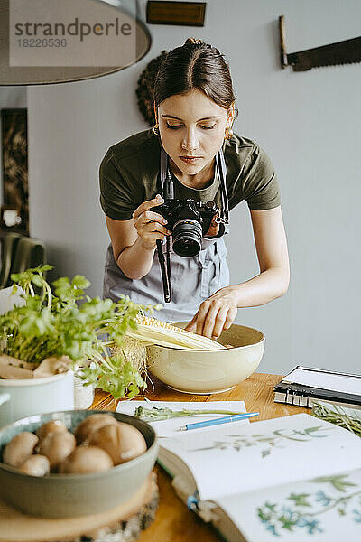 Food-Stylist fotografiert Gemüseschale mit Digitalkamera im Studio