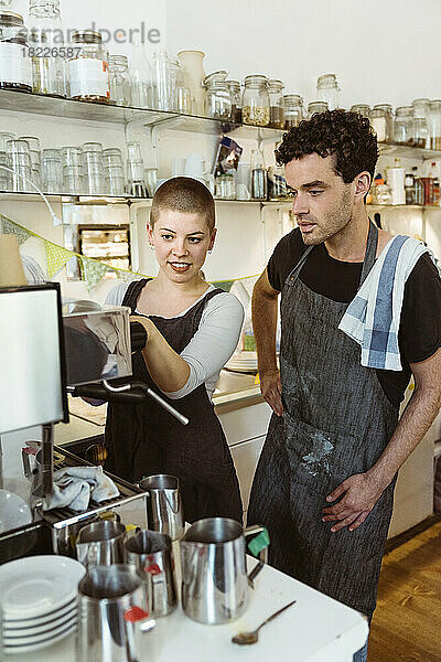 Weibliche und männliche Besitzer lernen den Umgang mit der Kaffeemaschine im Café