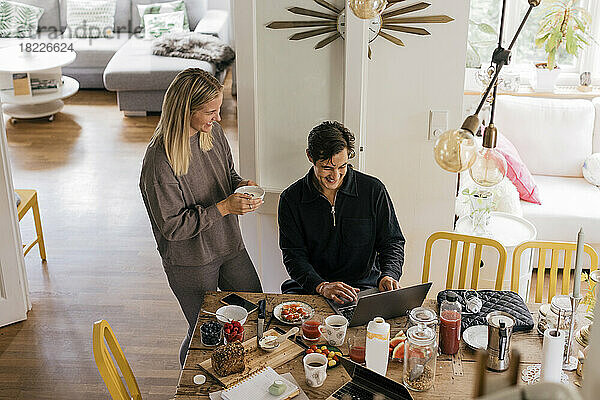 Blick von oben auf ein glückliches Paar beim Frühstück während der Arbeit zu Hause