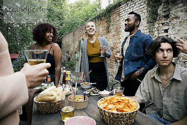 Männliche und weibliche Freunde verschiedener Rassen genießen Essen und Getränke auf einer Gartenparty