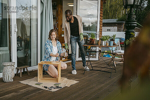 Älterer Mann sieht Frau an  die Möbel auf der Veranda vor dem Haus streicht