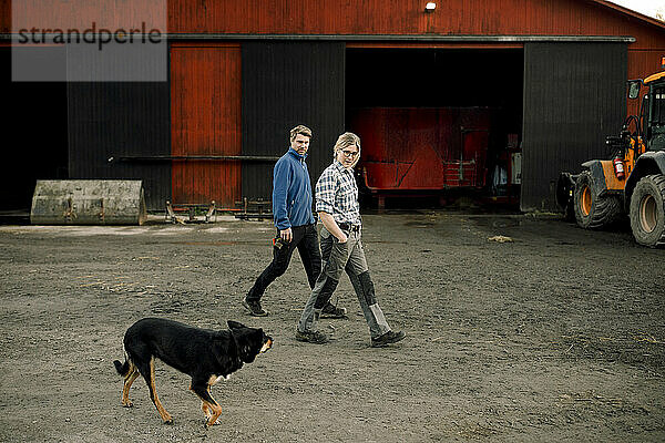 Landwirte mit Hund gehen gemeinsam vor der Fabrik spazieren