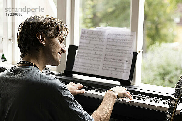 Leidenschaftlicher junger Mann spielt zu Hause Klavier