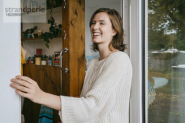 Glückliche junge Frau mit Pullover  die an der Tür steht