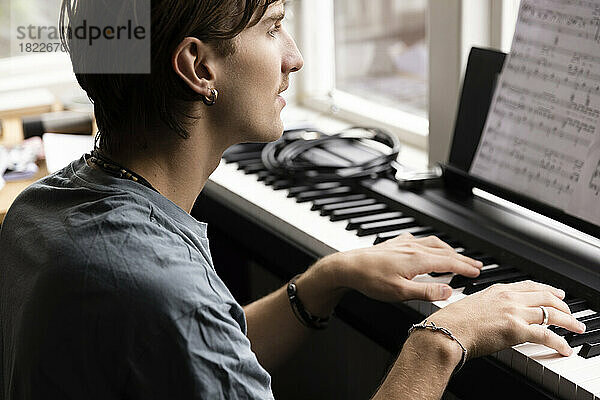 Konzentrierter junger Mann  der zu Hause Klavier übt