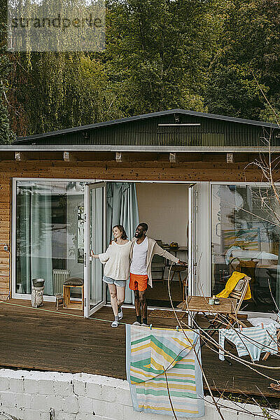 Ein gemischtrassiges Paar steht zusammen auf einer Veranda vor der Tür
