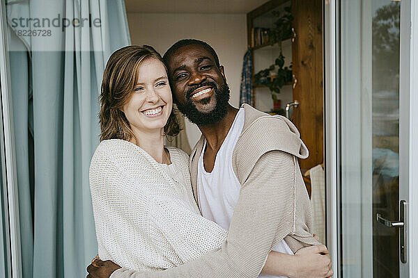 Glückliches multirassisches Paar  das sich an der Tür umarmt