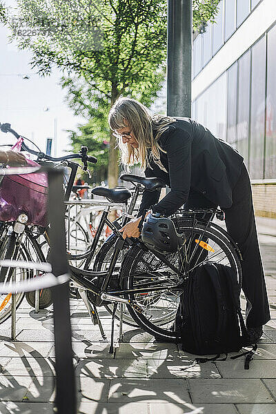 Geschäftsfrau schließt ihr Fahrrad an einer Parkstation ab