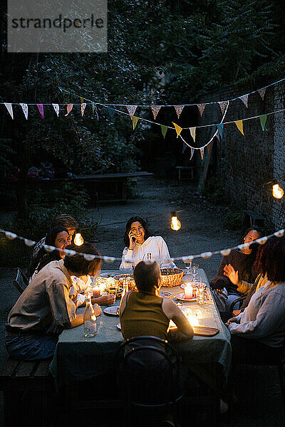 Freunde genießen ein Abendessen im mit Wimpeln geschmückten Hinterhof
